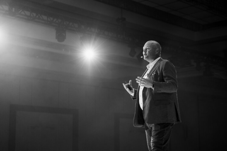 A black and white image of Jack Newton, CEO and Founder of Clio on stage.