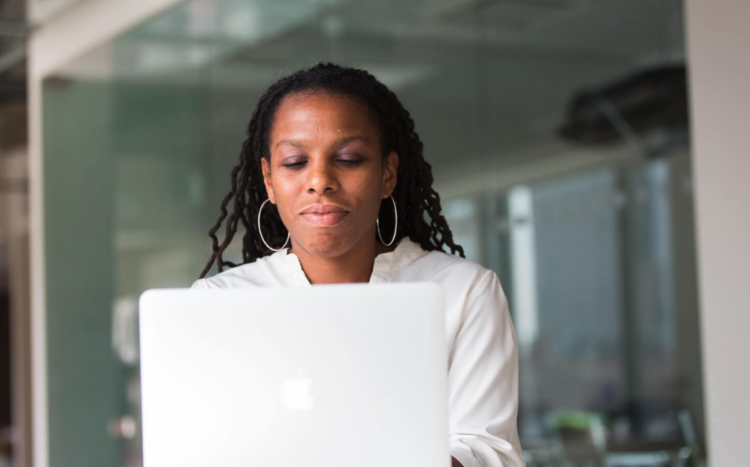 A lawyer sitting down typing on a laptop researching how to start their own firm without money.